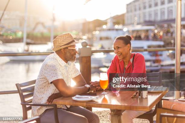 senior couple having a drink at an outdoor restaurant in cape town waterfront - old couple restaurant stock-fotos und bilder