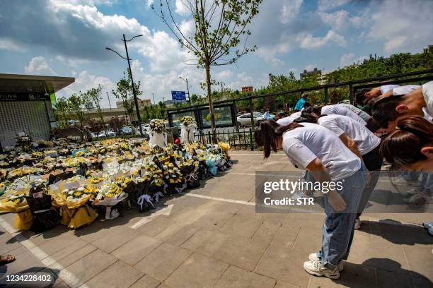 People bow in front of flower bouquets placed in front of a subway station in memory of flood victims in Zhengzhou, China's central Henan province on...