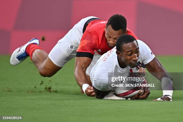 S Perry Baker scores a try despite a tackle from Britain's Dan Norton in the men's quarter-final rugby sevens match between Britain and the US during...