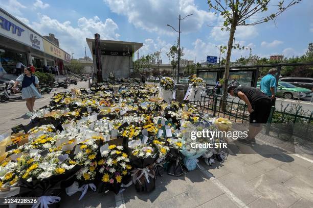 Man bows as people place flowers in front of a subway station in memory of flood victims in Zhengzhou, China's central Henan province on July 27,...