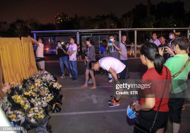 This photo taken on July 26, 2021 shows people placing flowers in front of a subway station as they mourn victims killed in flooding caused by heavy...