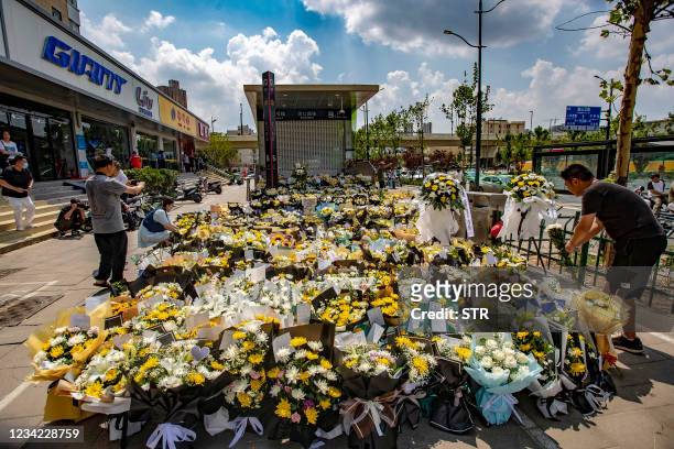 Man places flowers with other bouquets in front of a subway station in memory of flood victims in Zhengzhou, China's central Henan province on July...