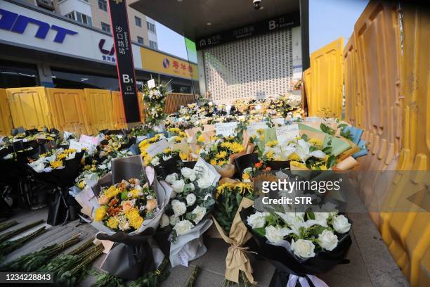 Flowers placed as tributes are seen in front of a subway station in memory of flood victims in Zhengzhou, China's central Henan province on July 27,...
