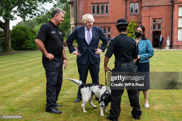 Prime Minister Boris Johnson, with Home Secretary Priti Patel, interact with Pete Greenfield, senior dog instructor and PC Suzanne West with Murphy,...