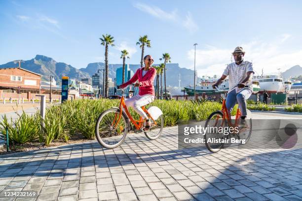 couple sightseeing on hired bicycles in city - kaapstad stockfoto's en -beelden