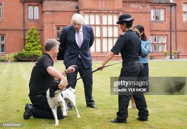 Britain's Prime Minister Boris Johnson and Britain's Home Secretary Priti Patel meet a police dog handler during a visit to Surrey Police...