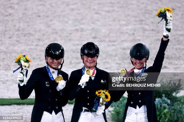 Gold medallists from team Germany Dorothee Schneider, Isabell Werth and Jessica von Bredow-Werndl pose on the podium after winning the dressage grand...