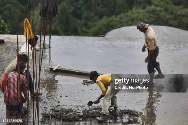 Workers and child labors cement a rooftop in preparation for construction for adding an additional level to a hotel in Pelling, Sikkim, India, on...