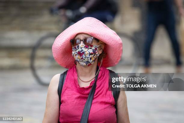 Pedestrian wears a facemask as she walks in Southbank, central London on July 27, 2021. - Prime Minister Boris Johnson called for caution Tuesday...