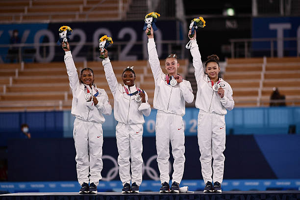 Silver medalists USA's Sunisa Lee, USA's Grace Mc Callum USA's Simone Biles and USA's Jordan Chiles wave on the podium of the artistic gymnastics...