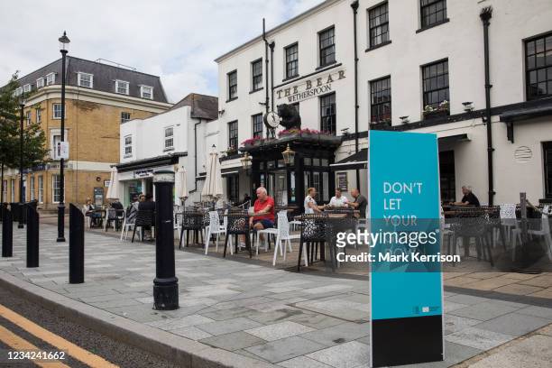 Covid-19 public health information sign is pictured in front of local residents enjoying refreshments outside a JD Wetherspoon public house on 27th...