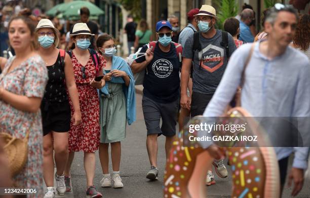 People, wearing protective masks, walk in a street of Biarritz, southwestern France, on July 27, 2021. - France's highest constitutional authority...