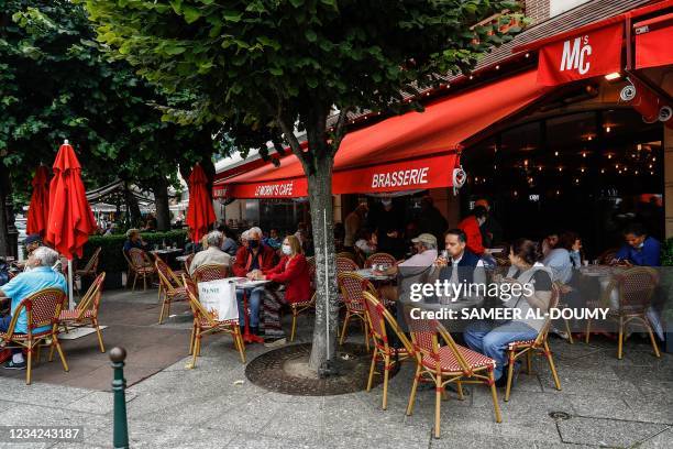 People sit around tables at a coffee shop after showing their Covid-19 health pass in Deauville on July 27, 2021. - France's highest constitutional...