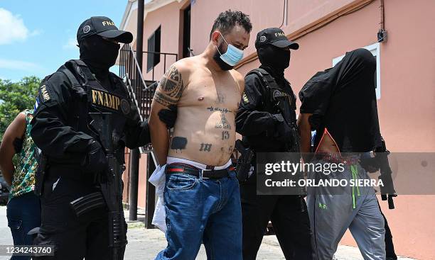 Members of the National Anti-Gang Force guard an alleged leader of the Mara Salvatrucha , captured along with two women and a minor, in a marginal...