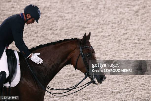 Steffen Peters of the US riding Suppenkasper caresses his horse after competing in the dressage grand prix special team competition during the Tokyo...