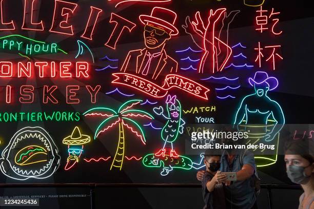 Visitors to the Grand Central Market take a photo with neon signs on Tuesday, July 27, 2021 in Los Angeles, CA.