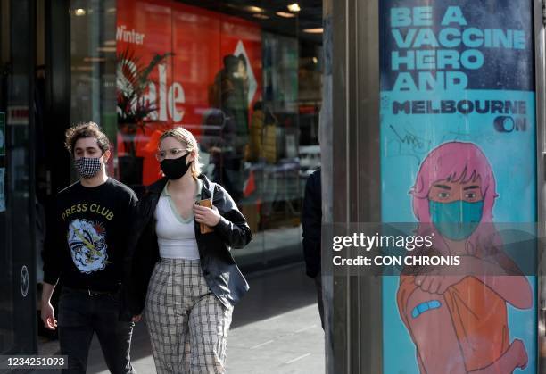 Couple walk past an advertisement promoting Covid-19 vaccinations in Melbourne on July 28 after the city's coronavirus lockdown was lifted on July 27...