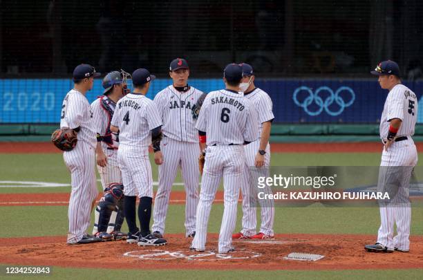 Japan's infield players gather around relief pitcher Ryoji Kuribayashi during the ninth inning of the Tokyo 2020 Olympic Games baseball opening round...