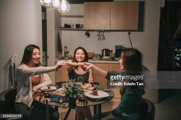 a group of asian chinese female friends having social gathering in apartment eating pizza in dining room at night - evening meal restaurant stock pictures, royalty-free photos & images