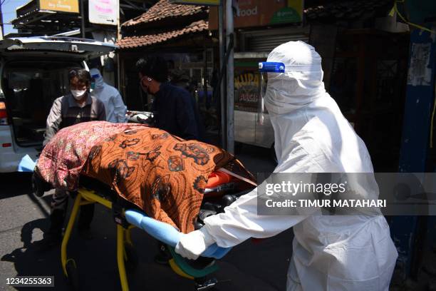 Health workers remove the body of a Covid-19 victim who died while isolating at home in Bandung on July 28 as coronavirus-slammed Indonesia reported...