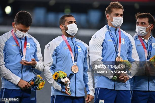 Bronze medallists Argentina's Gaston Revol stands with his teammates on the podium for the victory ceremony after the men's final rugby sevens match...