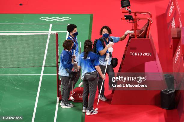 Volunteers gather in front of a referee's podium as they clean a court before badminton matches during the Tokyo 2020 Olympic Games at the Musashino...