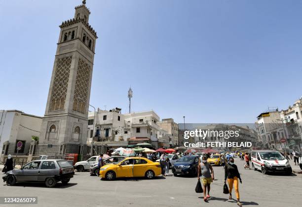 People walk past the Sidi Bashir mosque in the Bab el-Fellah area of Tunisia's capital Tunis on July 28, 2021. - Tunisia lurched further into...