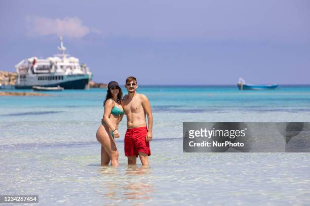 Young couple enjoys the water of Balos, as they run or walk in the water of Balos Beach, the incredible lagoon, with the pool like turquoise exotic...