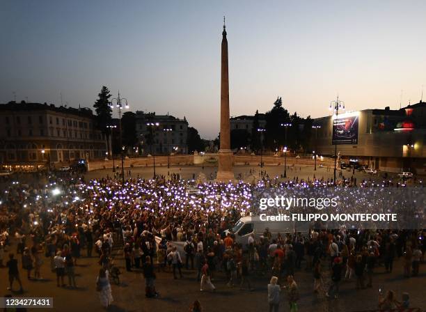 Protestors hold lights as they take part in a demonstration against the introduction of a mandatory 'green pass', in Piazza del Popolo in Rome, on...