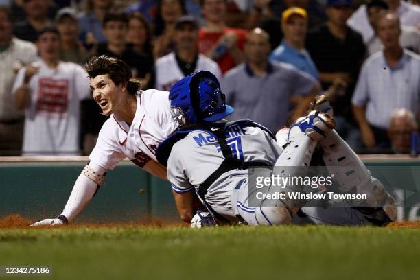 Jarren Duran of the Boston Red Sox scores against the tag of catcher Reese McGuire of the Toronto Blue Jays on his triple and an error in the fourth...