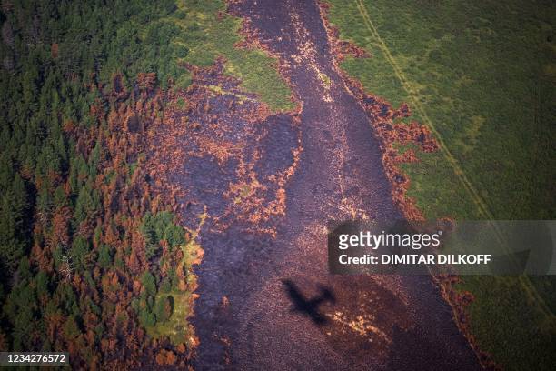 This photograph taken on July 27 shows the shadow of an aircraft of the Air Forest Protection Service flying over a burned forest in the republic of...