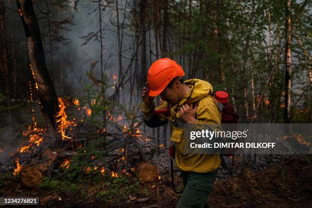 Member of Aerial Forest Protection Service monitors a backfire at the edge of the village of Byas-Kyuel, on July 26. 2021. - Fuelled by a June...