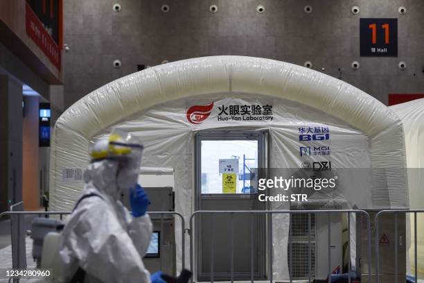 This photo taken on July 28, 2021 shows a staff member spraying disinfectant at a temporary "Fire Eye" laboratory used for Covid-19 coronavirus...