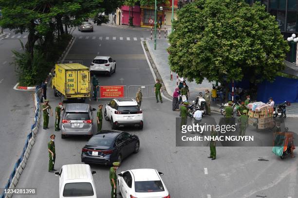Police personnel check travel documents at a check-point in Hanoi on July 29, 2021 amidst the government imposed two-week lockdown to stop the spread...