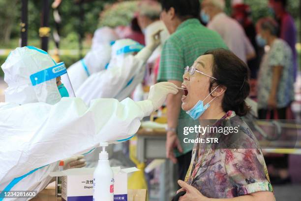 Woman receives a nucleic acid test for the Covid-19 coronavirus in Nanjing, in eastern Jiangsu province on July 29, 2021. - China OUT / China OUT