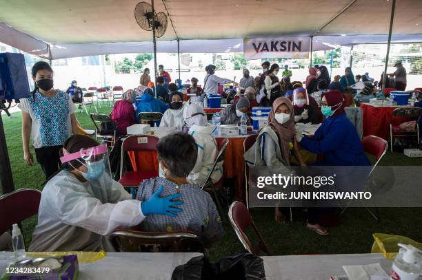 Residents receive the Sinovac Covid-19 coronavirus vaccine at a makeshift mass vaccination centre on a football field in Surabaya on July 29, 2021.
