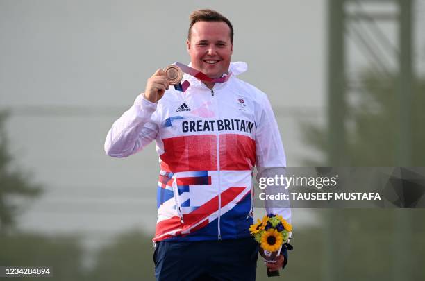 Bronze medallist Britain's Matthew John Coward Holley stands on the podium for the victory ceremony of the men's trap final during the Tokyo 2020...