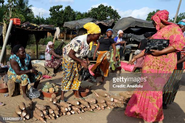 People shop from a woman street vendor in Abidjan, Ivory Coast on July 28, 2021.