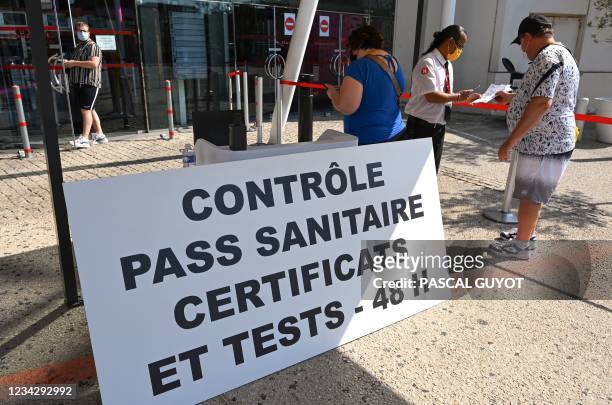 Visitors present their health pass to an official at the entrance to The Gaumont Multiplex Odyséum Cinema in Montpellier, southern France on July 29,...