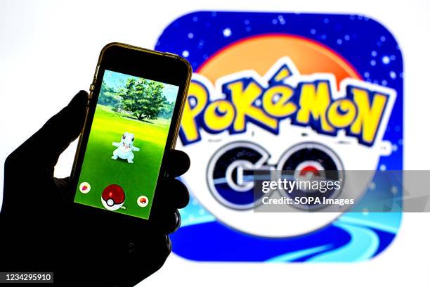 In this photo illustration a Pokémon GO app seen displayed on a smartphone with a Pokémon GO logo in the background.