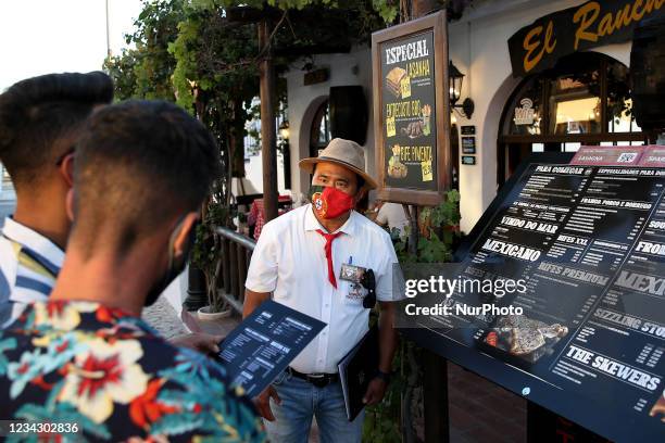 Waiter presents the menu to customers outside a restaurant in Albufeira, Portugal on July 29, 2021. Portuguese Prime Minister Antonio Costa announced...