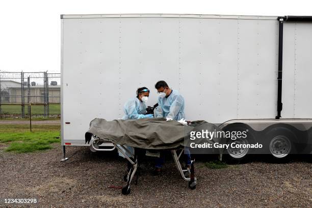 Border Patrol agents Nancy Balo, left, and Jerry Passement, take detail photographs of the finger prints of the remains of deceased female migrant,...