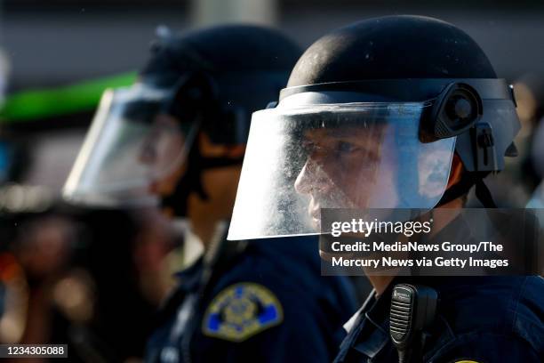 An officer looks on as people protest the police killing of George Floyd on East Santa Clara Street in downtown San Jose on Friday, May 29, 2020.