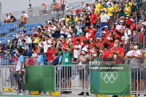 July 2021, Japan, Tokio: Rowing: Olympics, men's eight, finals in Sea Forest Waterway. Team members and athletes stand in one area of the grandstand...