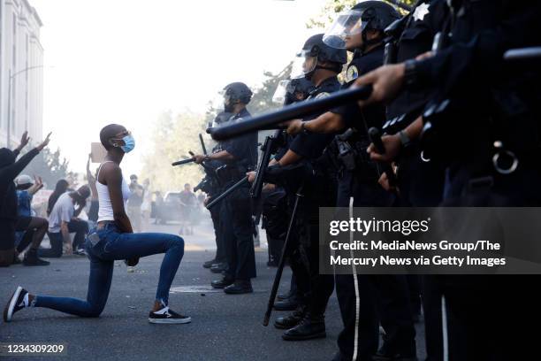 Protester takes a knee in front of San Jose Police officers during a protest on East Santa Clara Street in San Jose, Calif., on May 29 after the...