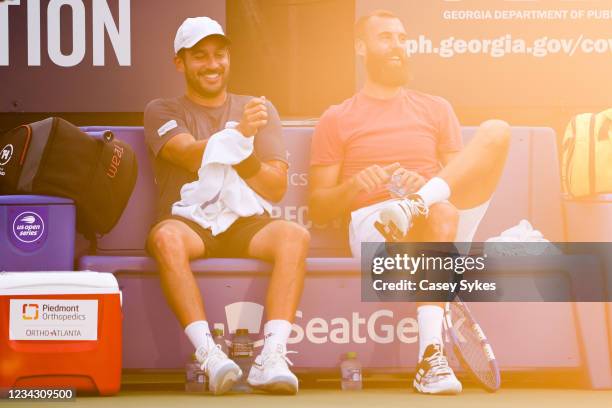 Treat Huey of the Philippines and Benoit Paire of France laugh together on the bench during a doubles match against Reilly Opelka of the United...