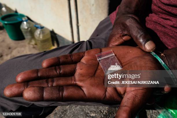 Crystal meth user holds in his palm one gramme of crystal meth which he bought from a local dealer for USD $3.00 while sitting at the back of a house...