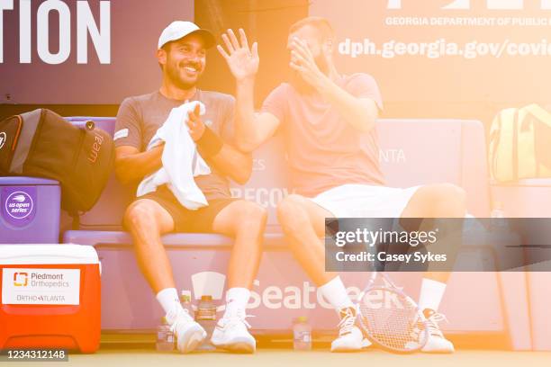 Treat Huey of the Philippines and Benoit Paire of France smile as they talk together on the bench during a doubles match against Reilly Opelka of the...