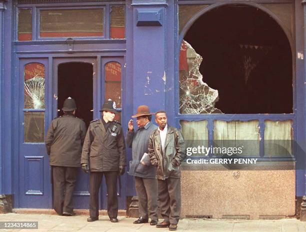 Police and members of the local community chat outside the burnt out Atlantic Pub 14 December following the overnight riots in the streets of...