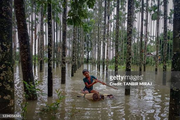 Child wades through a flooded area using a makeshift raft at Maulovir Para, Cox's Bazar on July 30, 2021 after monsoon floods and landslides have cut...